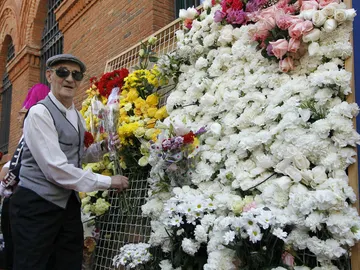Un chulapo cuelga una flor en la ofrenda a la Virgen de la Paloma Un chulapo cuelga una flor en la ofrenda a la Virgen de la Paloma