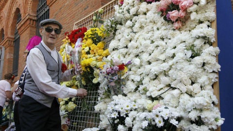 Un chulapo cuelga una flor en la ofrenda a la Virgen de la Paloma