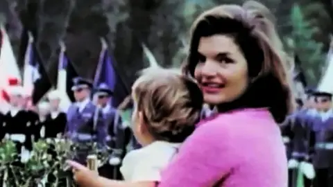 Jackie Kennedy posa con su hijo en brazos en un desfile militar. Jackie Kennedy posa con su hijo en brazos en un desfile militar.