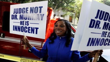 Una mujer sostiene carteles en las que anuncia que el doctor Conrad Murray es inocente.