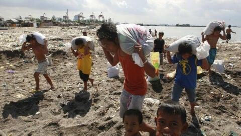 Varias personas transportan sacos en Filipinas para impedir el paso del agua