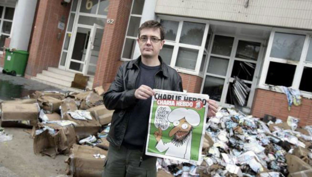 El editor del semanario frente a la sede de la revista y con portada de la polémica