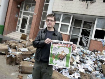 El editor del semanario frente a la sede de la revista y con portada de la polémica