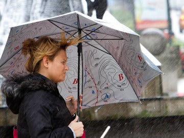 Una mujer se protege del viento y la lluvia en Pontevedra