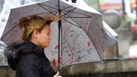 Una mujer se protege del viento y la lluvia en Pontevedra