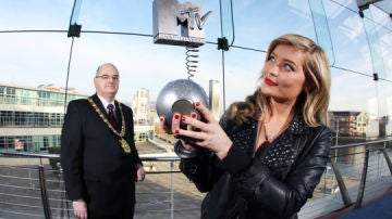 El alcalde de Belfast, Pat Convery, (al fondo), posa junto a la estatuilla, en manos de una reportera de la cadena. 