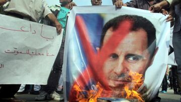 Manifestantes queman una pancarta con la fotografía del presidente sirio, Bachar al Asad