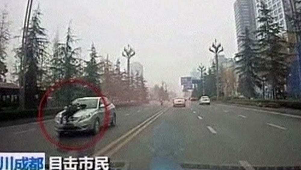 Un policía chino sobre el capó de un taxi ilegal