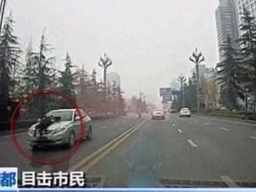 Un policía chino sobre el capó de un taxi ilegal