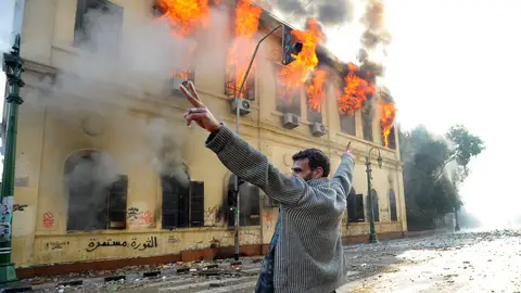 Un manifestante realiza el símbolo de la victoria frente a un edificio en llamas en El Cairo Un manifestante realiza el símbolo de la victoria frente a un edificio en llamas en El Cairo