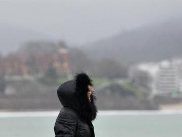  Una mujer se protege del frío y la lluvia hoy en el paseo de La Concha de San Sebastián