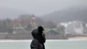  Una mujer se protege del frío y la lluvia hoy en el paseo de La Concha de San Sebastián