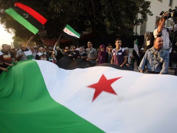Manifestantes sujetan una gran bandera de Siria Manifestantes sujetan una gran bandera de Siria