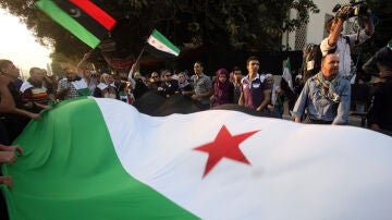 Manifestantes sujetan una gran bandera de Siria