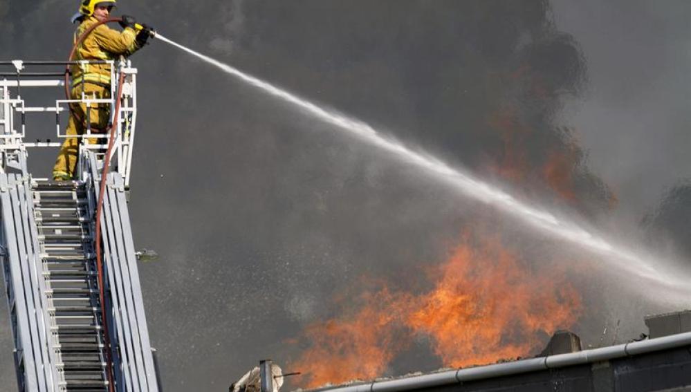 Un bombero echa agua sobre el incendio de la fábrica de puertas "Portas Vilanova"