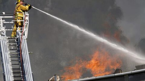 Un bombero echa agua sobre el incendio de la f&aacute;brica de puertas "Portas Vilanova"