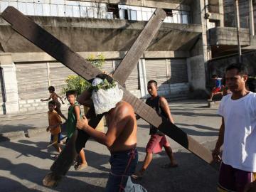 Un penitente filipino porta una gran cruz en una calle de la ciudad de San Fernando, Filipinas