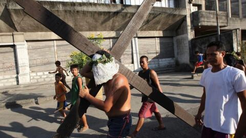 Un penitente filipino porta una gran cruz en una calle de la ciudad de San Fernando, Filipinas