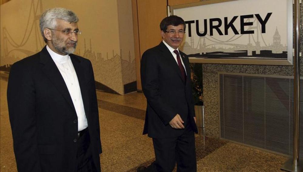 El ministro turco de Exteriores Ahmet Davutoglu camina junto al jefe de la delegación iraní