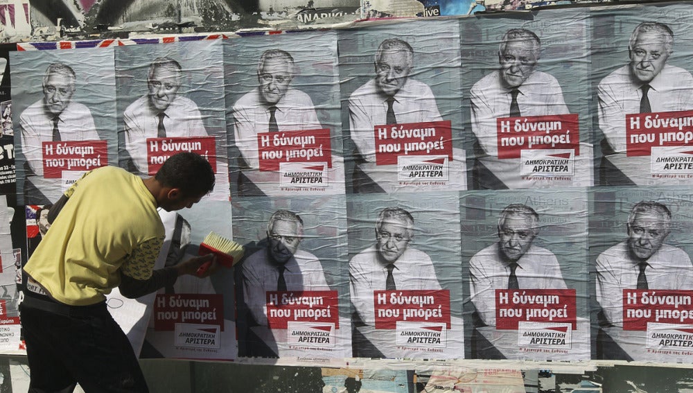 Un joven pega carteles electorales en Atenas