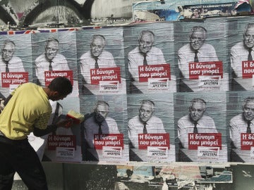 Un joven pega carteles electorales en Atenas Un joven pega carteles electorales en Atenas