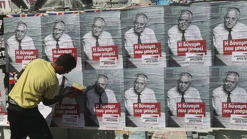 Un joven pega carteles electorales en Atenas Un joven pega carteles electorales en Atenas