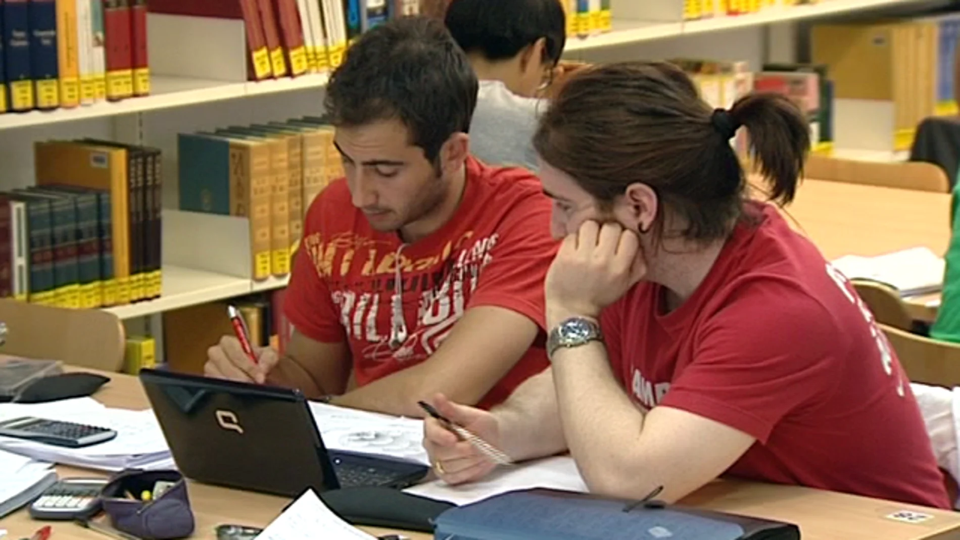 Dos jóvenes estudian en una biblioteca Dos jóvenes estudian en una biblioteca