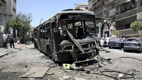 Oficiales de seguridad inspeccionan la zona donde ha explosionado un veh&iacute;culo policial 