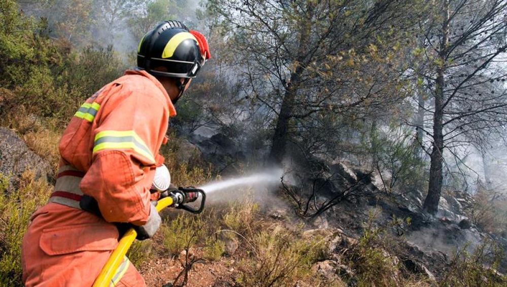 Un bombero combate el incendio que afecta al término municipal de Villalonga