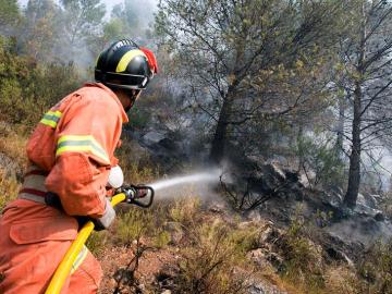 Un bombero combate el incendio que afecta al término municipal de Villalonga