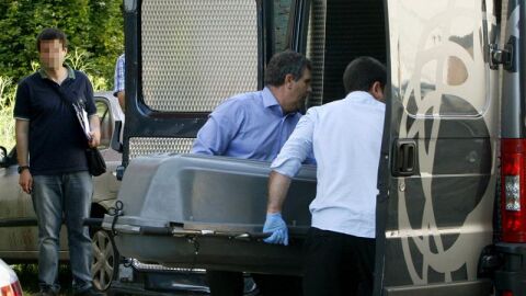 Miembros de servicios funerarios trasladan un cuerpo sin vida