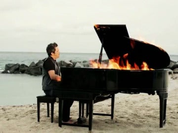 Alejandro Sanz toca un piano en llamas en la playa.