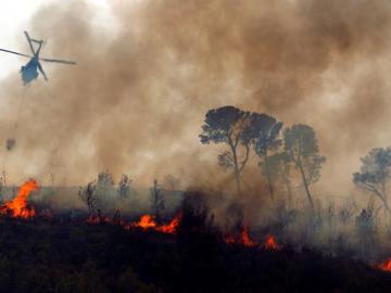 Un helicóptero vuela sobre el fuego durante los trabajos de extinción Un helicóptero vuela sobre el fuego durante los trabajos de extinción