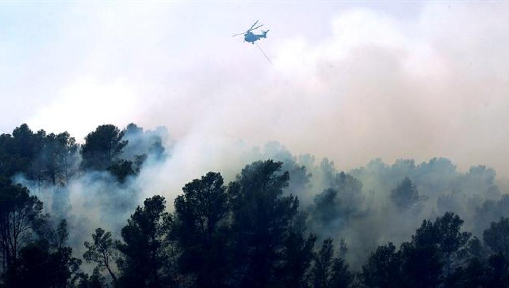 Un helicóptero vuela sobre el fuego durante los trabajos de extinción