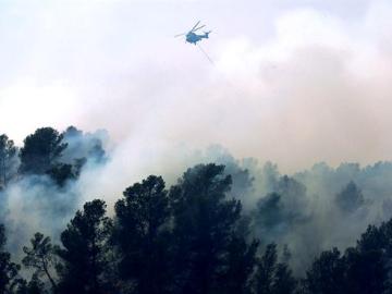 Un helicóptero vuela sobre el fuego durante los trabajos de extinción