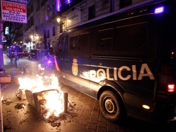 Dos furgones de la Policía Nacional junto a cubos de basura ardiendo Dos furgones de la Policía Nacional junto a cubos de basura ardiendo