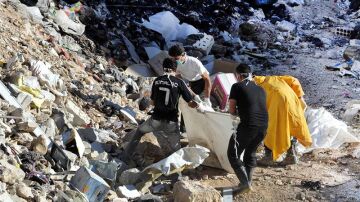 Personas llevan cuerpos mutilados a un cementerio en el área de Yalda, 10 kilómetros al sur de Damasco