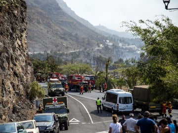 Varios coches de bomberos cortan el tráfico en el límite del incendio forestal en la isla 
