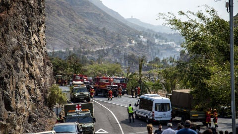 Varios coches de bomberos cortan el tr&aacute;fico en el l&iacute;mite del incendio forestal en la isla 