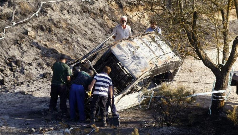 Efectivos de la Guardia Civil junto a un coche quemado