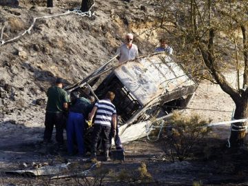 Efectivos de la Guardia Civil junto a un coche quemado