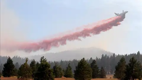Un avión libera retardante para combatir un incedio Un avión libera retardante para combatir un incedio