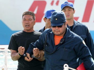 Policías japoneses escoltan a un activista de Hong Kong detenido por la guardia costera de Japón tras desembarcar en las islas Diaoyu, en chino, o Senkaku, en japonés