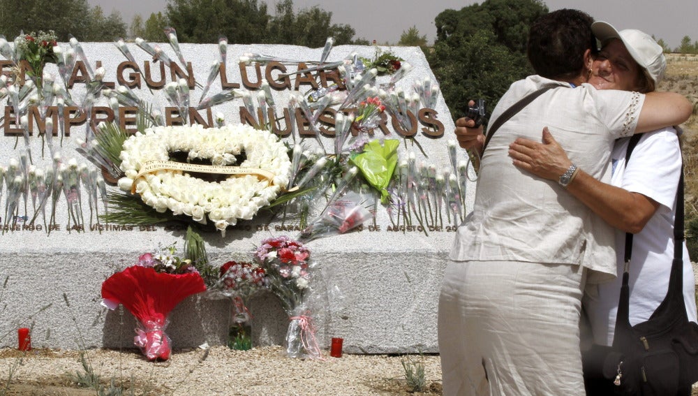 Familiares de las víctimas se abrazan ante la piedra de granito conmemorativa levantada en el lugar donde se produjo el accidente