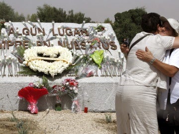 Familiares de las víctimas se abrazan ante la piedra de granito conmemorativa levantada en el lugar donde se produjo el accidente