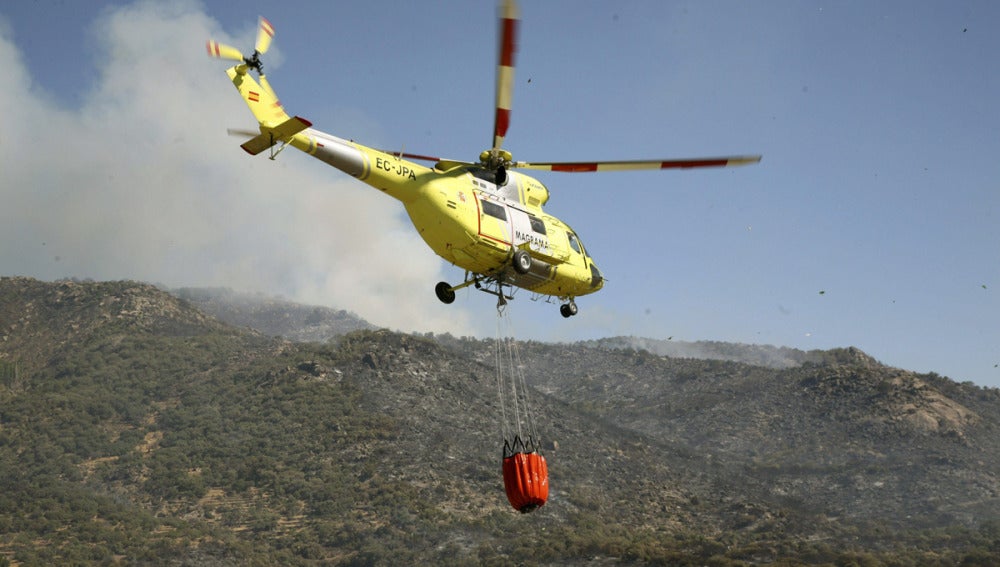 Un helicóptero lleva agua para arrojar sobre el incendio 