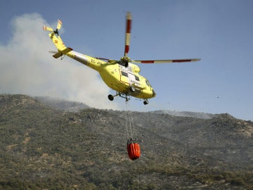 Un helicóptero lleva agua para arrojar sobre el incendio 