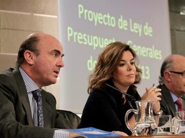 El ministro de Economía, Luis de Guindos, junto a la vicepresidenta del Gobierno, Soraya Sáenz de Santamaría, y el titular de Hacienda y Administraciones Públicas, Cristóbal Montoro