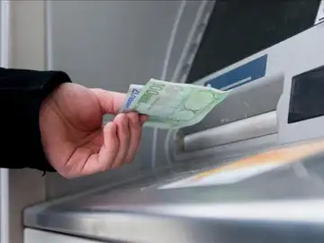 Un hombre saca dinero de un cajero Un hombre saca dinero de un cajero