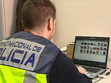 Un policía comprueba archivos de pornografía en un ordenador Un policía comprueba archivos de pornografía en un ordenador